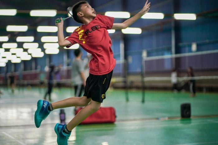 boy-playing-badminton-in-sports-hall