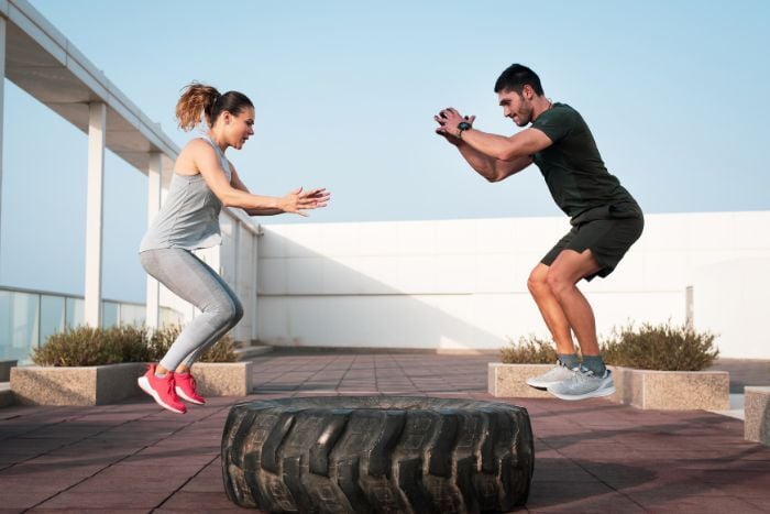 couple-doing-tire-squat-jumps