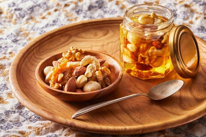 jar-of-honey-with-mixed-nuts-on-wooden-plate