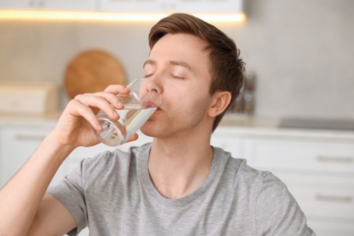 man-drinking-water-from-glass-in-kitchen