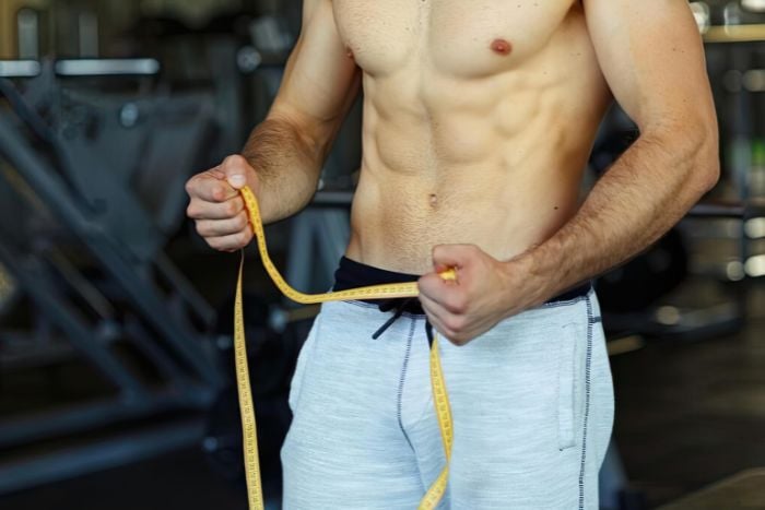 man-measuring-waist-in-gym