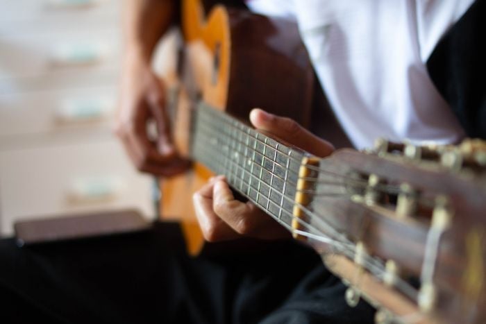 person-playing-brown-acoustic-guitar