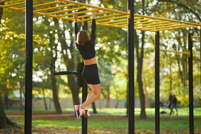 woman-hanging-on-monkey-bars-outdoors