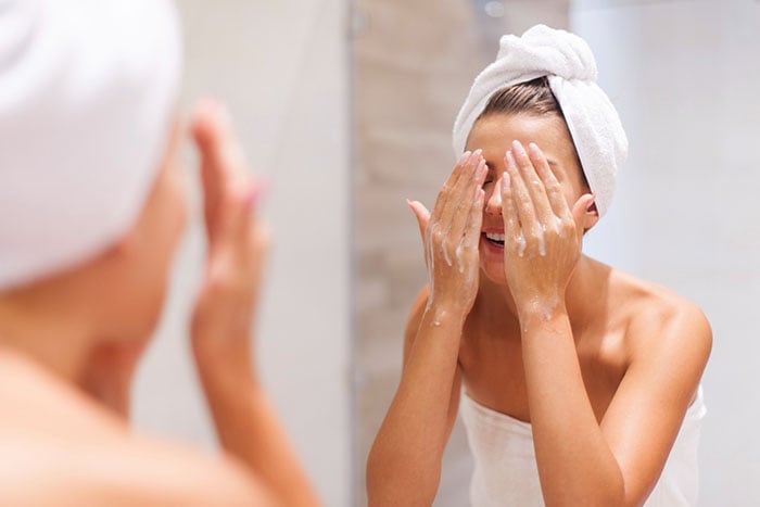 woman-washing-face-in-bathroom