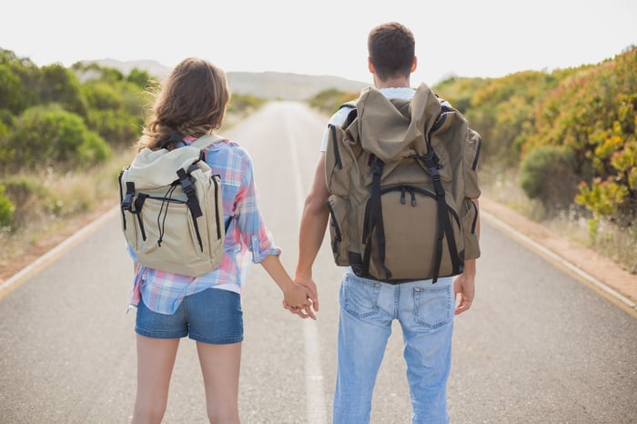 Rear view of hiking young couple standing on countryside road