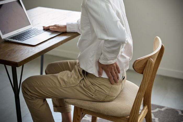 man-experiencing-back-pain-while-working-at-a-desk