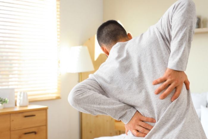 young-man-suffering-from-back-pain-in-bedroom
