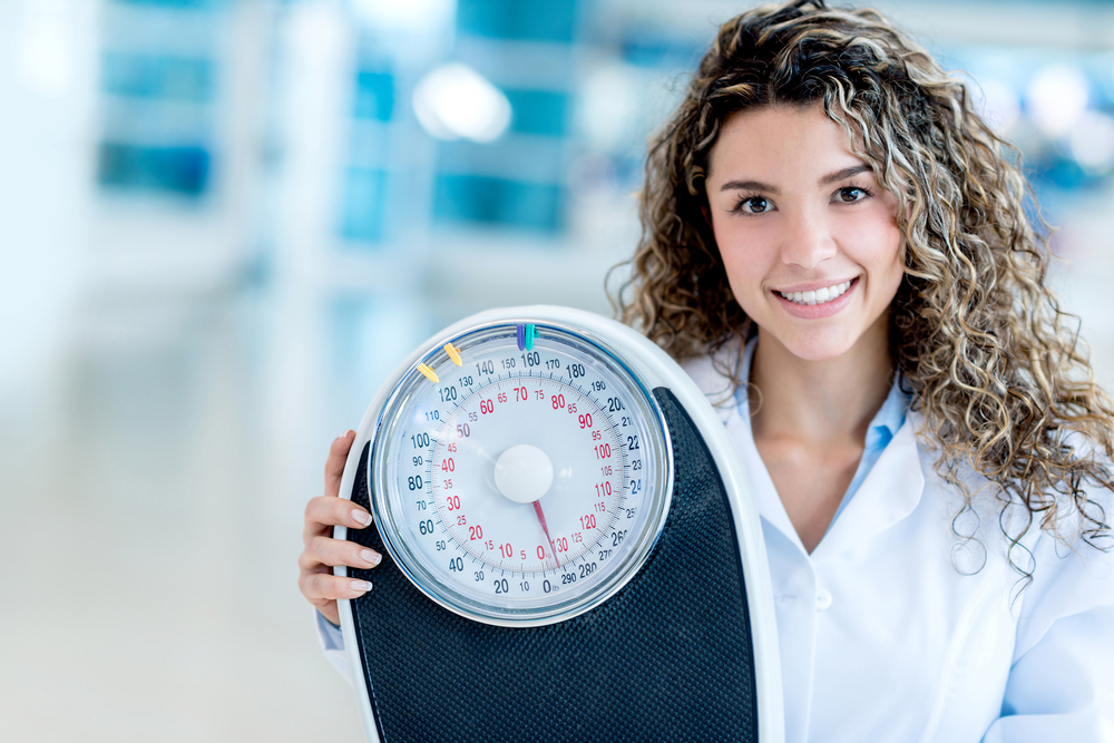 Female nutritionist at the hospital holding a weight scale