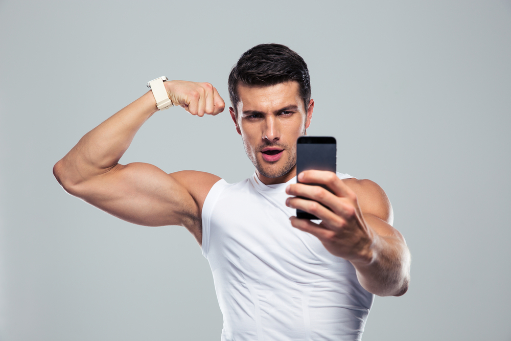Sports man making selfie photo on smartphone over gray background-2