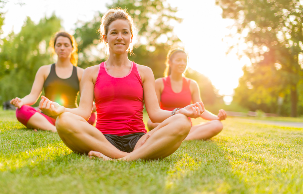 horizontal detail of women doing yoga outdoors at sunset with lens flare. Defocused